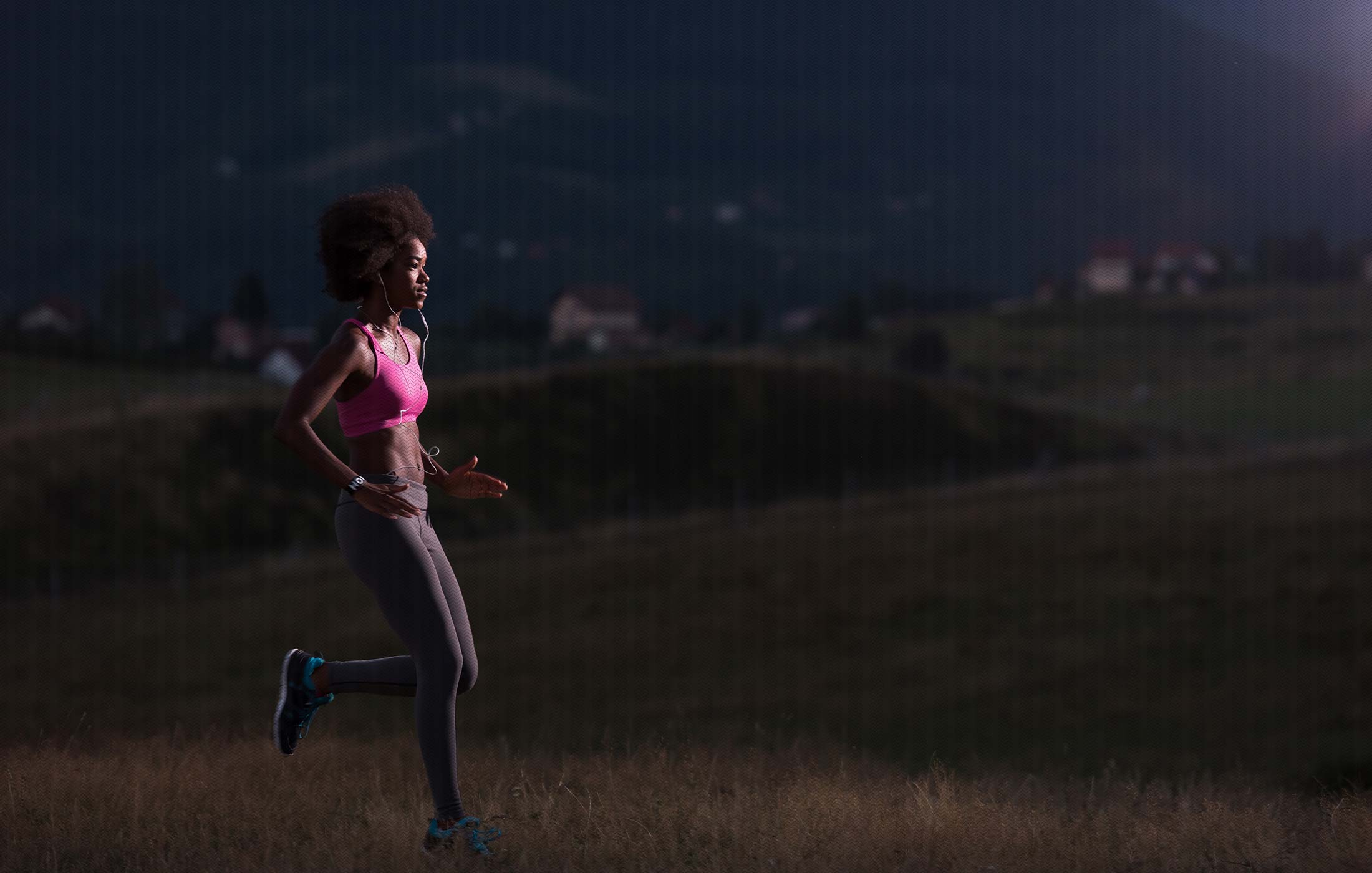 Woman running in field at dusk